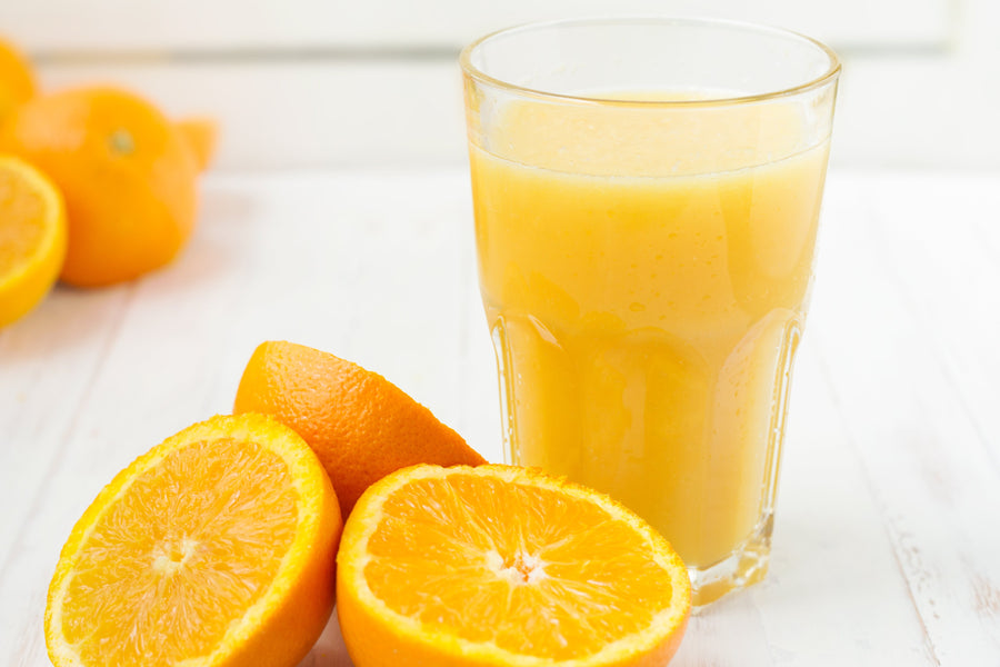 Glass of orange juice and oranges sliced in half